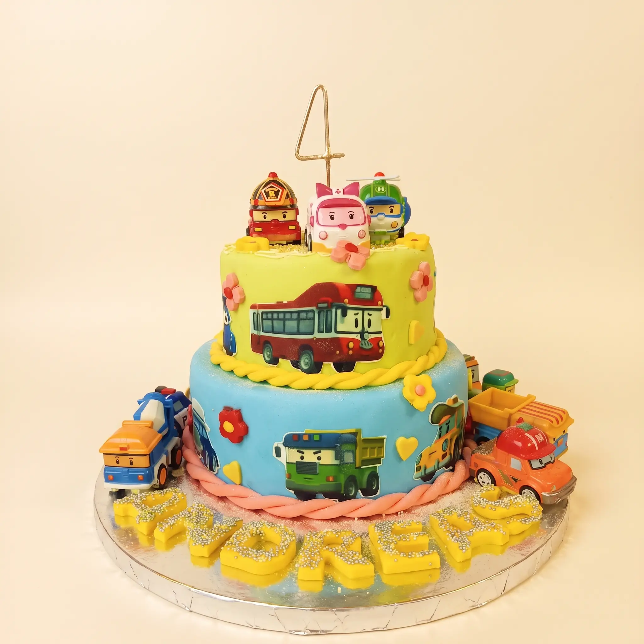 Colourful two-tier children’s birthday cake with vehicle decorations and a number four topper